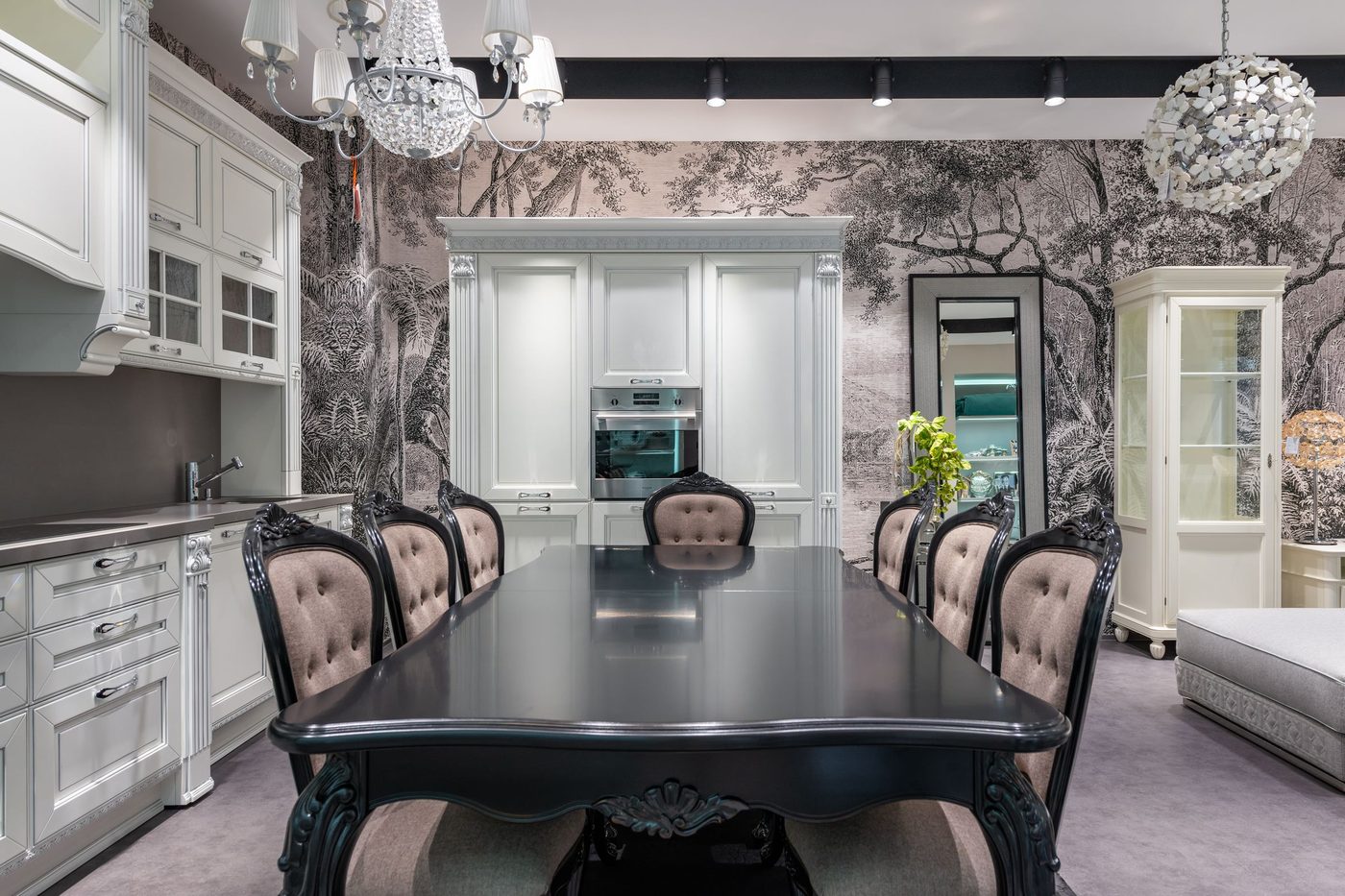 Dining room with a monochrome tree-canopy mural wallpaper, a dark oval table with upholstered chairs and white cabinetry
